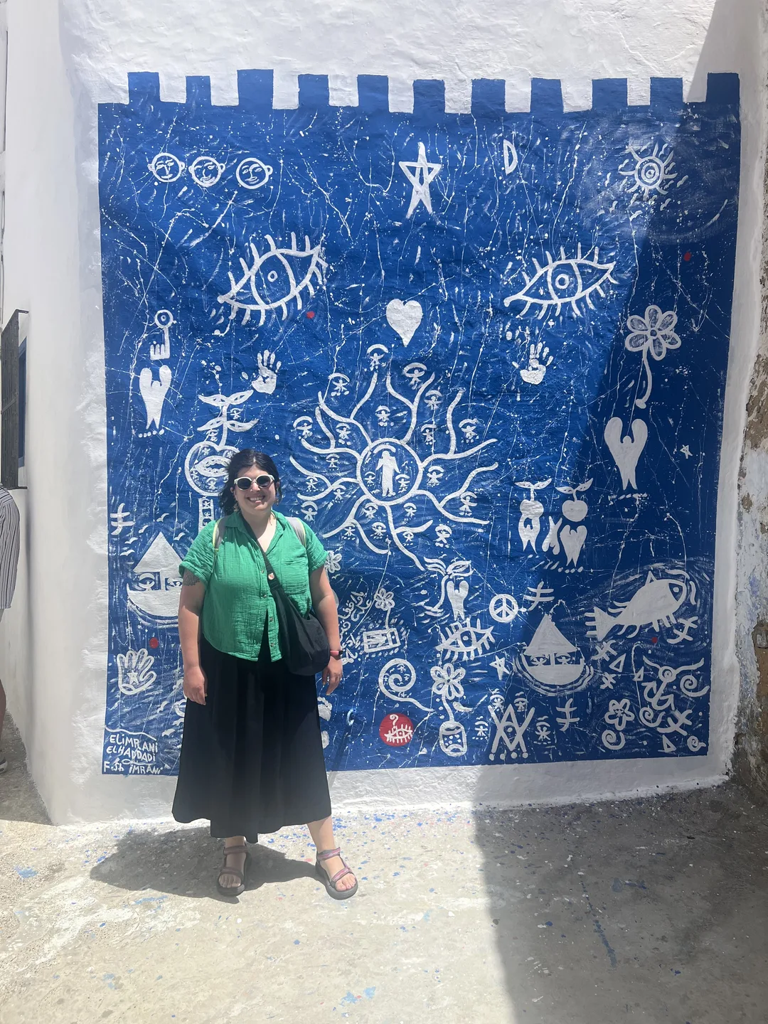 Photo of Gabi in front of a blue and white mural in the medina of Asilah, Morocco